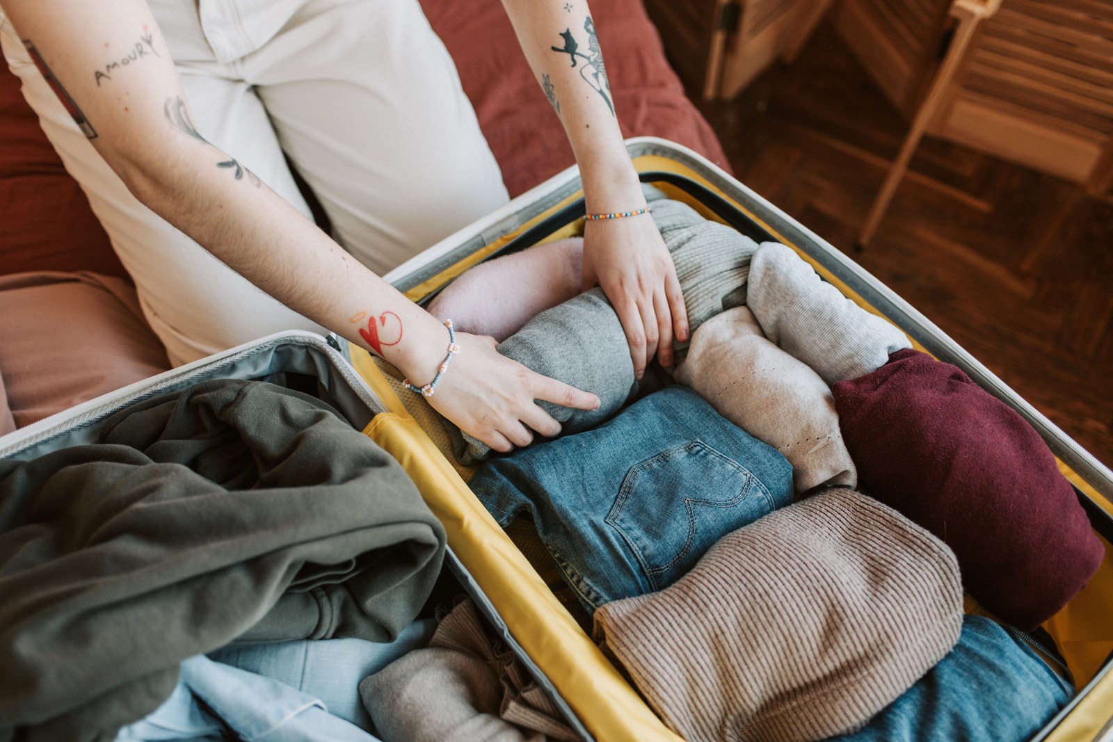 Hands packing rolled clothes into a suitcase